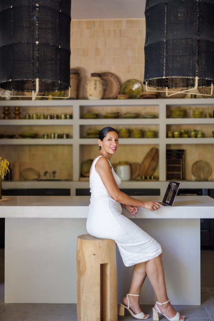 Nedjma assise sur un tabouret en bois devant son ordinateur